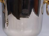 a silver ice bucket with gold handles on a white table