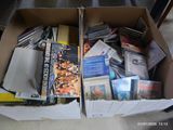 une boîte en carton remplie de livres et de DVD posée par terre