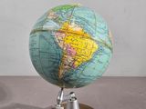 un petit globe posé sur un socle en bois, sur une table