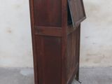 a small wooden cabinet with a door open on a sidewalk
