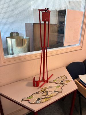 une petite table sur laquelle se trouve un dessin, devant une fenêtre