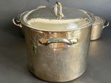 a large metal pot with a lid on a table