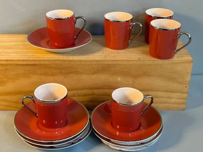 quatre tasses et soucoupes rouges posées sur un support en bois