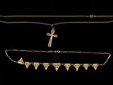 three gold necklaces and a cross on a black background