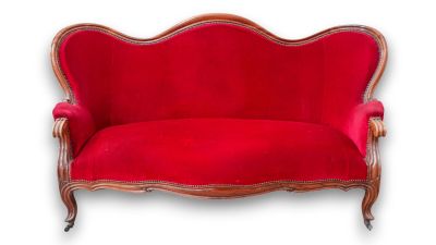 a red couch sitting on top of a wooden floor next to a white wall