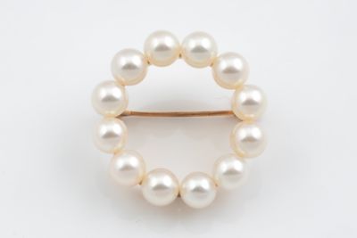 un gros plan d'une broche ornée de perles sur fond blanc