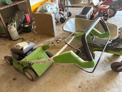 une petite tondeuse à gazon verte rangée dans un garage