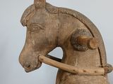 a small wooden horse with a wooden handle on it ' s back