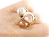 a woman ' s hand holding a ring with three pearls on it
