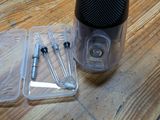 a plastic container with two screws and a pair of scissors on a wooden table