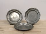 trois assiettes en argent posées sur une table en bois