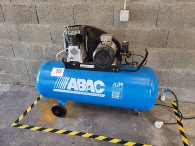 an air compressor sitting on top of a blue tank in front of a brick wall