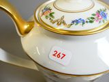 une théière blanche avec une anse dorée et des motifs floraux