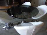 a glass table with white chairs and a black top