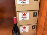 une bouteille de vin posée sur une étagère à côté de cartons de vin