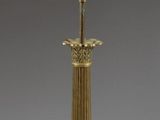 an antique brass table lamp with a black shade on top of it