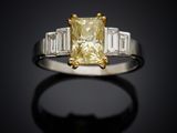 a close up of a yellow diamond ring with baguets on a black background