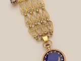 a gold and lapel pin with a blue glass pendant