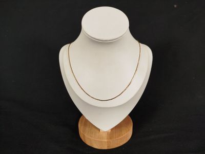 a close up of a white mannequin with a gold chain on it