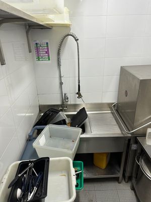 a kitchen with a sink and a trash can in it