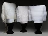 trois serviettes blanches sont alignées les unes à côté des autres sur un mannequin