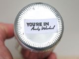 a person holding a bottle with a sticker on it that says you ' re in andy marshall