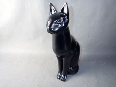 a black cat statue sitting on a white surface