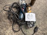 an image of a corded electric driller sitting on the ground next to a pole