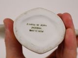 a person holding a small white bowl with writing on it