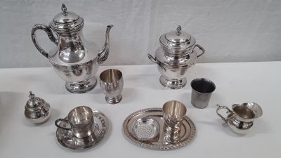 a silver tea set on a table with silver cups and saucers