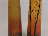 two tall vases with trees painted on them sitting next to each other