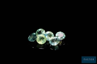 a close up of three different colored gems on a black surface