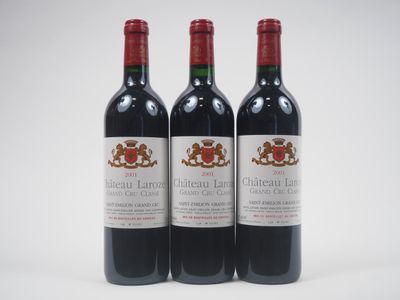 trois bouteilles de vin rouge posées l'une à côté de l'autre sur une surface blanche
