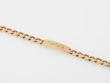 un bracelet en or jaune avec des maillons de type « curb » sur fond blanc