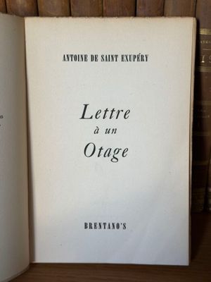 un vieux livre posé sur une table en bois, à côté d'une pile de livres