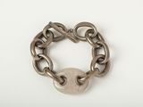bracelet à maillons orné d'un cadenas, posé sur un fond blanc