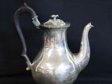 an antique silver tea pot with a handle on a black background