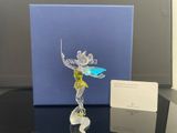 La figurine est posée sur une table, à côté d'une boîte bleue.