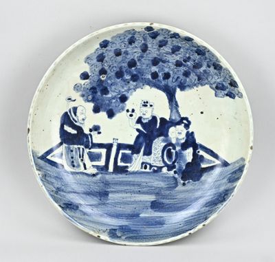 une assiette bleue et blanche sur laquelle sont représentés un homme et une femme dans un bateau