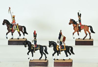 four figurines of men in uniforms riding horses on wooden bases