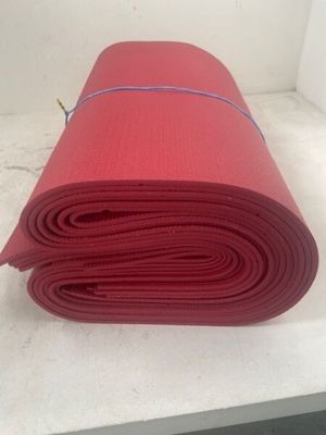 un tapis de yoga rouge enroulé sur un plan de travail blanc