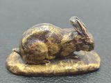 une image représentant une figurine de lapin en bronze posée sur un rocher
