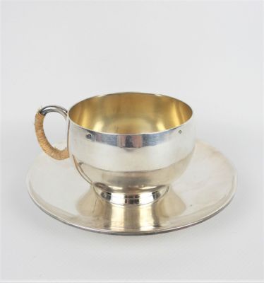 une tasse et une soucoupe en argent posées sur une soucoupe