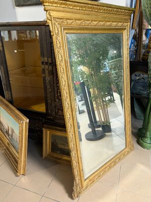un grand miroir posé sur une table, à côté d'un vase