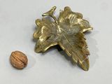 a gold leaf and a walnut on a white surface