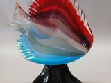 a glass fish that is sitting on a black stand