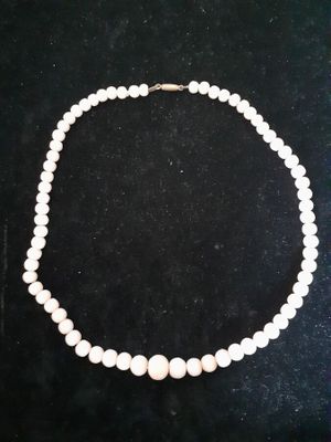 a white pearl necklace with a gold clasp on a black background