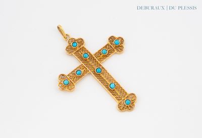 a close up of a gold cross with turquoise stones on it