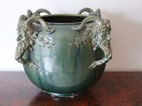 a green vase with two rams on it sitting on a table