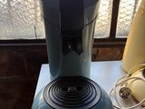 une cafetière bleue posée sur une table à côté d'une banane
